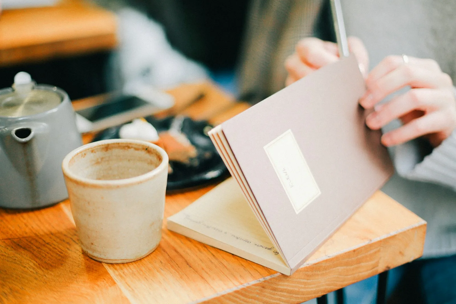 person writing in a book near coffee cup